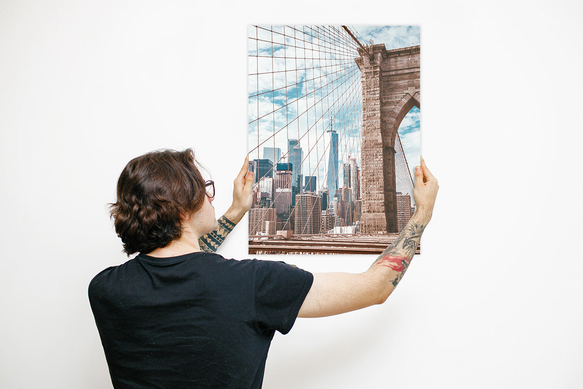 A man hanging his create your own metal print of the Brooklyn bridge in New York